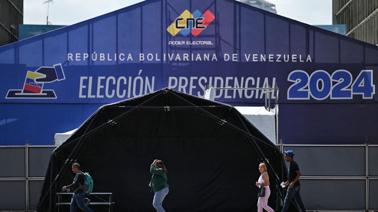 People walk in front of the media center of the National Electoral Council (CNE) in Caracas on July 27, 2024. . Venezuela will hold presidential elections on July 28, 2024. (Photo by JUAN BARRETO / AFP) (Photo by JUAN BARRETO/AFP via Getty Images)