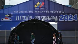 People walk in front of the media center of the National Electoral Council (CNE) in Caracas on July 27, 2024. . Venezuela will hold presidential elections on July 28, 2024. (Photo by JUAN BARRETO / AFP) (Photo by JUAN BARRETO/AFP via Getty Images)