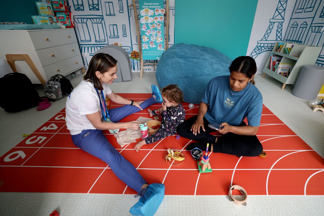 Panamanian artistic gymnast Hillary Heron interacts with her coach Yareimi Vazquez (L) and her daughter Aitana Vazquez inside a nursery room in the Athletes' Village ahead of the Paris Olympic Games.