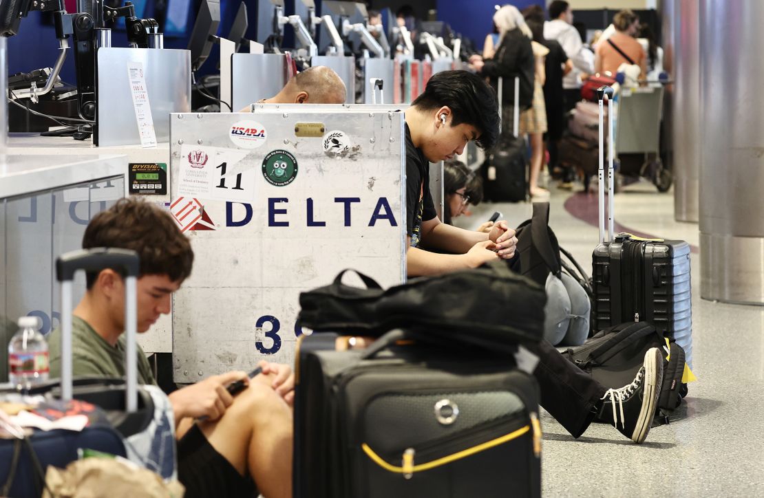 Travelers sit with their luggage on the check-in floor of the Delta Air Lines terminal at Los Angeles International Airport (LAX) on July 23, 2024 in Los Angeles, California.