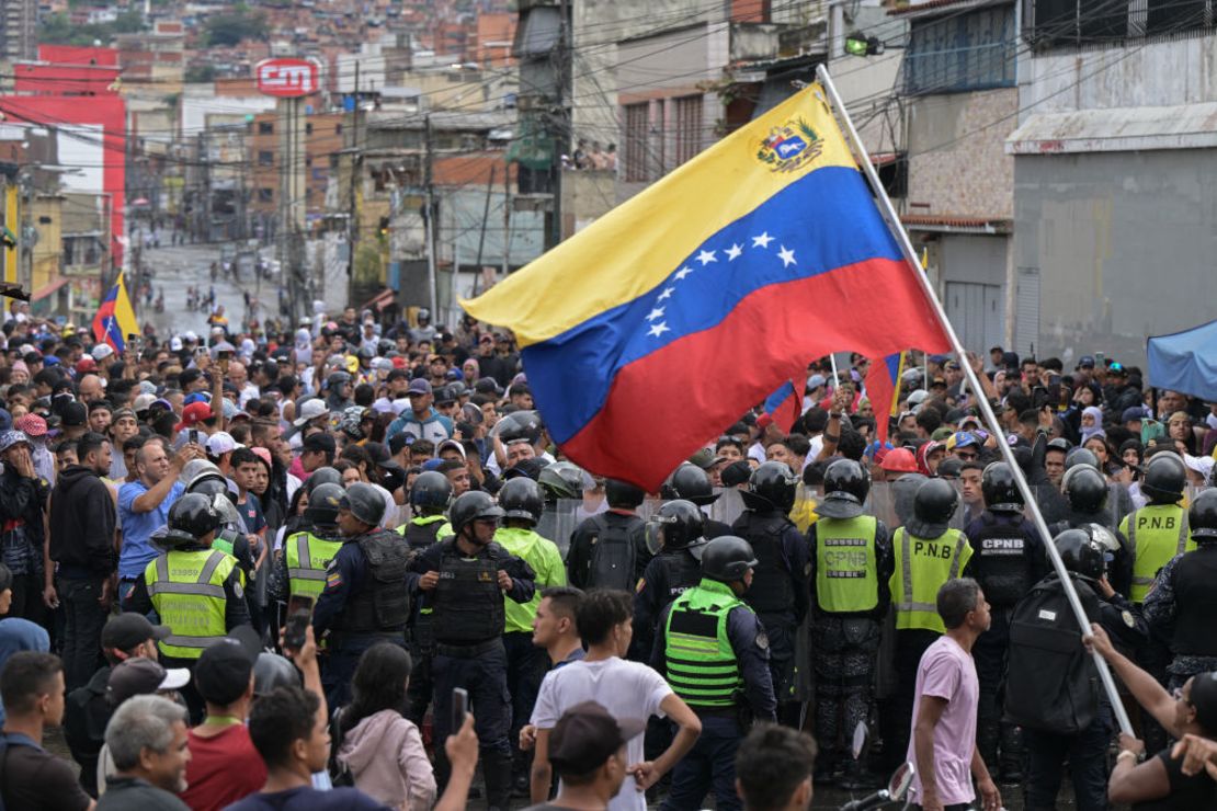 Un hombre ondea una bandera venezolana mientras los manifestantes chocan con agentes de policía durante una protesta contra el gobierno del presidente Nicolás Maduro en Caracas el 29 de julio de 2024, un día después de las elecciones presidenciales venezolanas. (YURI CORTEZ/AFP via Getty Images).