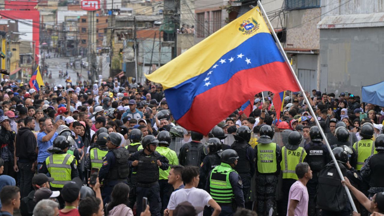 A man waves a Venezuelan flag as demonstrators clash with police officers during a protest against President Nicolas Maduro's government in Caracas on July 29, 2024, a day after the Venezuelan presidential election. Protests erupted in parts of Caracas Monday against the re-election victory claimed by Venezuelan President Nicolas Maduro but disputed by the opposition and questioned internationally, AFP journalists observed. (Photo by Yuri CORTEZ / AFP) (Photo by YURI CORTEZ/AFP via Getty Images)