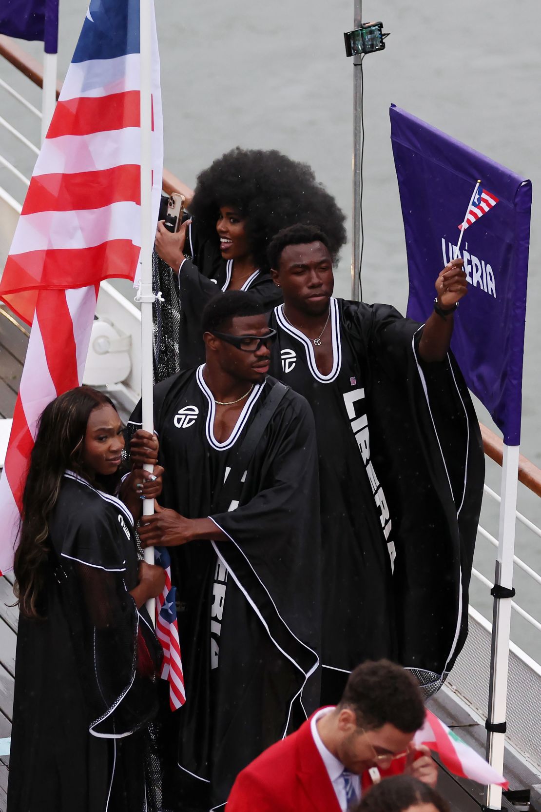 Left to right, Thelma Davies and Emmanuel Matadi, flagbearers of Team Liberia, were waving their flag along the River Seine during the opening ceremony. Their robes were designed by New York brand Telfar.