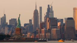 The sun sets on the Empire State Building and the Statue of Liberty in New York City seen from Bayonne, New Jersey on July 26