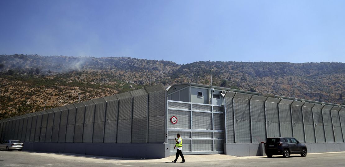 An Albanian walks in front of the main gate talking on a radio at an Italian-run migrant center located within an old military camp in Gjader, near Lezhe, on July 29, 2024.