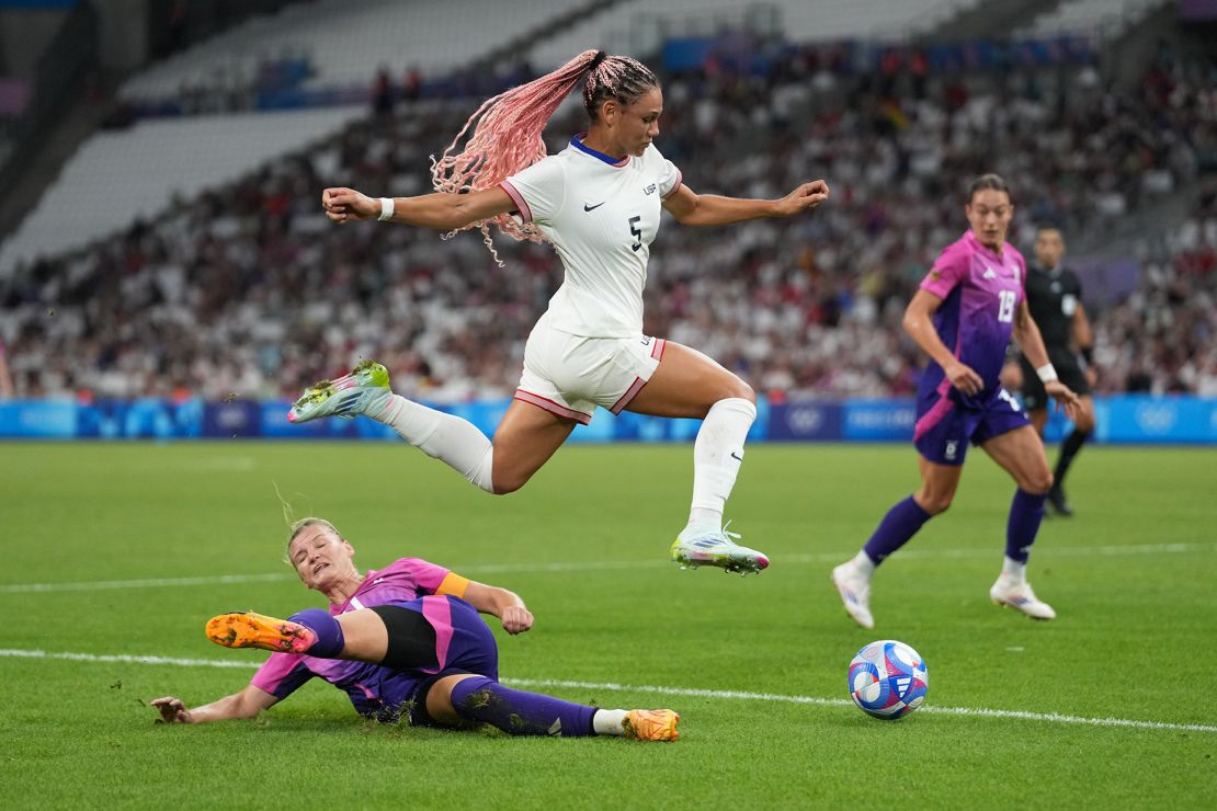 Trinity Rodman (center) of the United States jumps over the tackle of Alexandra Popp (left) of Germany during the Paris Olympics 2024.