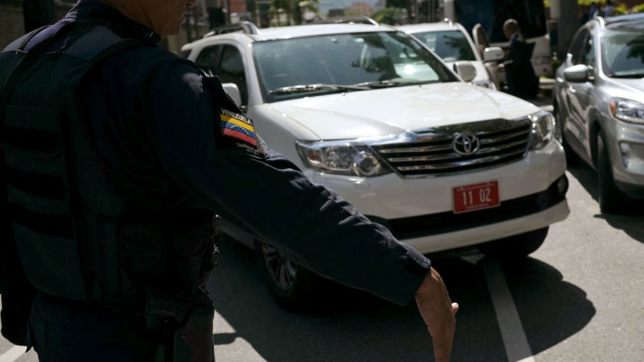 An officer of the Bolivarian National Police escorts a car transporting members of the Argentina's diplomat body in Venezuela as they leave Argentina's embassy in Caracas on August 1, 2024. The Argentine government on July 30, 2024, complained of "harassment" at its embassy in Venezuela, a day after President Nicolas Maduro's government ordered a slew of South American diplomats to leave Caracas for questioning his election win. (Photo by YURI CORTEZ / AFP) (Photo by YURI CORTEZ/AFP via Getty Images)