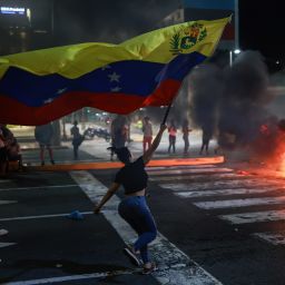 A protester runs waving a Venezuelan flag during a protest against the official results of the presidential election on July 29, 2024 in Caracas, Venezuela. Incumbent president Maduro was announced as the winner of a controversial presidential election with the 51,20% of the votes while opposition candidate Edmundo Gonzalez of the Plataforma Unitaria Democr·tica Coalition got the 44,2% according to the 'Consejo Nacional Electoral' CNE (National Electoral Council).