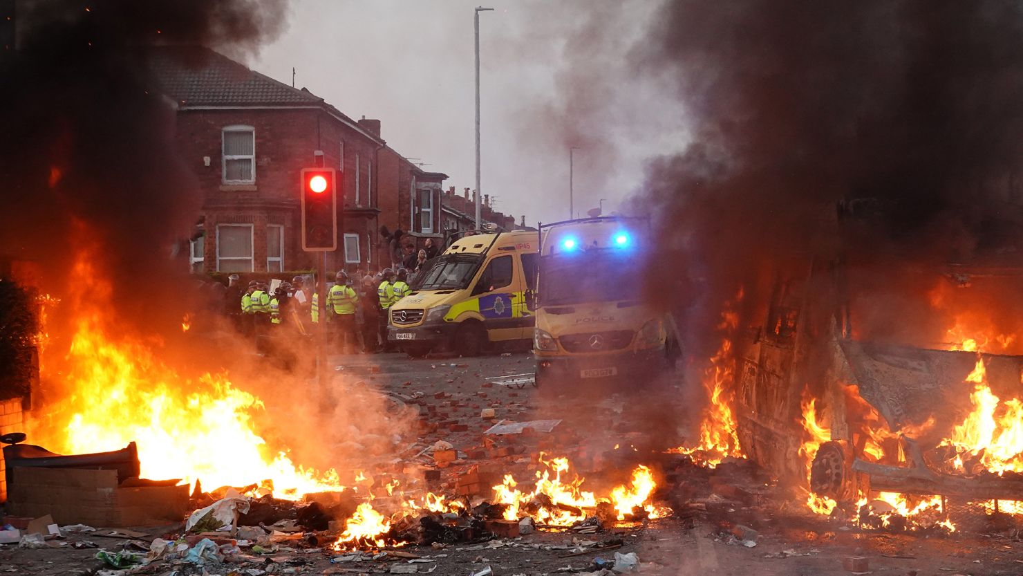 Police hold back rioters near a burning police vehicle after disorder broke out on July 30, 2024, in Southport, England.