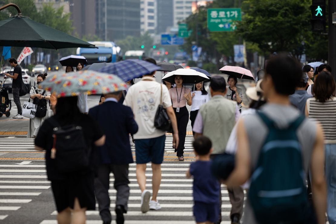 Pedestrians holding umbrellas cross a street in Seoul, South Korea, on Monday, Aug. 5, 2024. South Korea's fertility rate is the lowest in the world, at 0.72 children per woman in 2023.