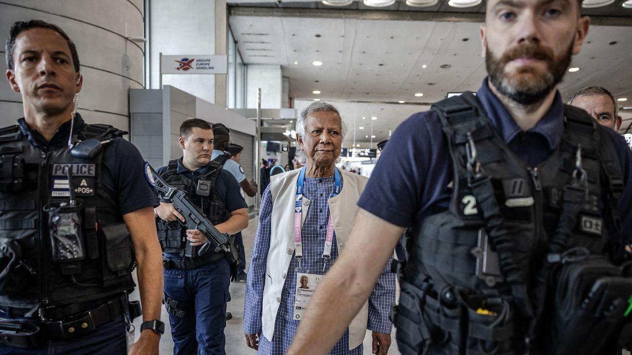 Bangladesh's finance pioneer Muhammad Yunus (C) is escorted by French police personnel as he arrives at Roissy-Charles de Gaulle Airport, north of Paris on August 7, 2024, enroute to Bangladesh, where he is set to lead a caretaker government after mass protests ousted premier Sheikh Hasina. Nobel-winner Muhammad Yunus will lead Bangladesh through a "democratic process" when he arrives in the country to helm an interim government, army chief Waker-Uz-Zaman said. (Photo by Luis TATO / AFP) (Photo by LUIS TATO/AFP via Getty Images)