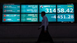 TOKYO, JAPAN - AUGUST 05: A pedestrian walks past monitors displaying the Nikkei 225 Stock Average figure outside a securities firm on August 05, 2024 in Tokyo, Japan. The Nikkei 225 index in Tokyo experienced a significant decline, plunging nearly 7% on August 4, 2024, as it fell to around 33,488.08 points shortly after the market opened. This drop, which came close to being a historic sell-off, is part of a broader global sell-off driven by concerns over the U.S. economy's stability amid high interest rates and disappointing hiring data, which has erased earlier gains that brought the Nikkei to all-time highs earlier this year. (Photo by Tomohiro Ohsumi/Getty Images)