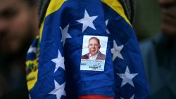 A woman covered with a Venezuelan flag and a sticker of Opposition candidate Edmundo Gonzalez Urrutia, attends a vigil called by the opposition demanding freedom for political prisoners arrested during protest following the contested re-election of Venezuelan President Nicolas Maduro in Caracas, August 8, 2024. Venezuela's opposition warned of a potential mass exodus of migrants if President Nicolas Maduro remains in power following his contested reelection, with the US calling on the strongman not to arrest protest leaders. (Photo by Yuri CORTEZ / AFP) (Photo by YURI CORTEZ/AFP via Getty Images)