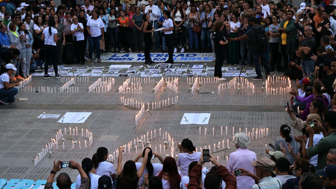 People surround lit candles forming the words 'Freedom and Peace' during a vigil called by the opposition demanding freedom for political prisoners arrested during protest following the contested re-election of Venezuelan President Nicolas Maduro in Caracas, August 8, 2024. Venezuela's opposition warned of a potential mass exodus of migrants if President Nicolas Maduro remains in power following his contested reelection, with the US calling on the strongman not to arrest protest leaders. (Photo by Yuri CORTEZ / AFP) (Photo by YURI CORTEZ/AFP via Getty Images)