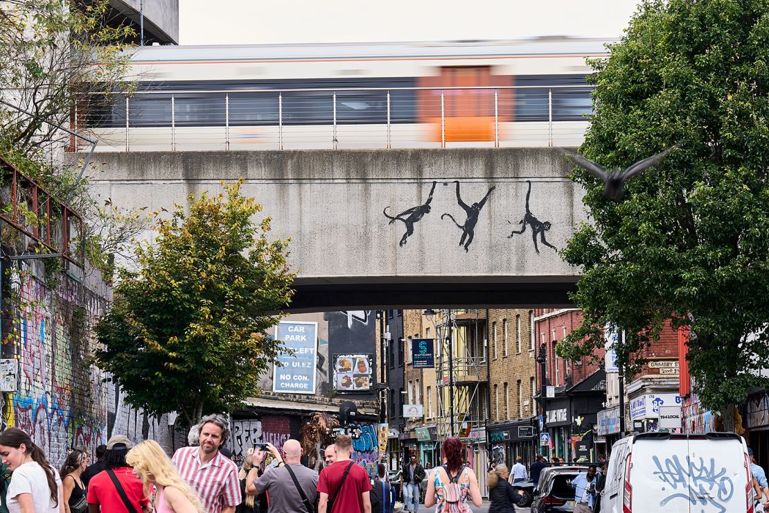 Three monkeys by Banksy adorn a bridge over Brick Lane in London on August 7, 2024.