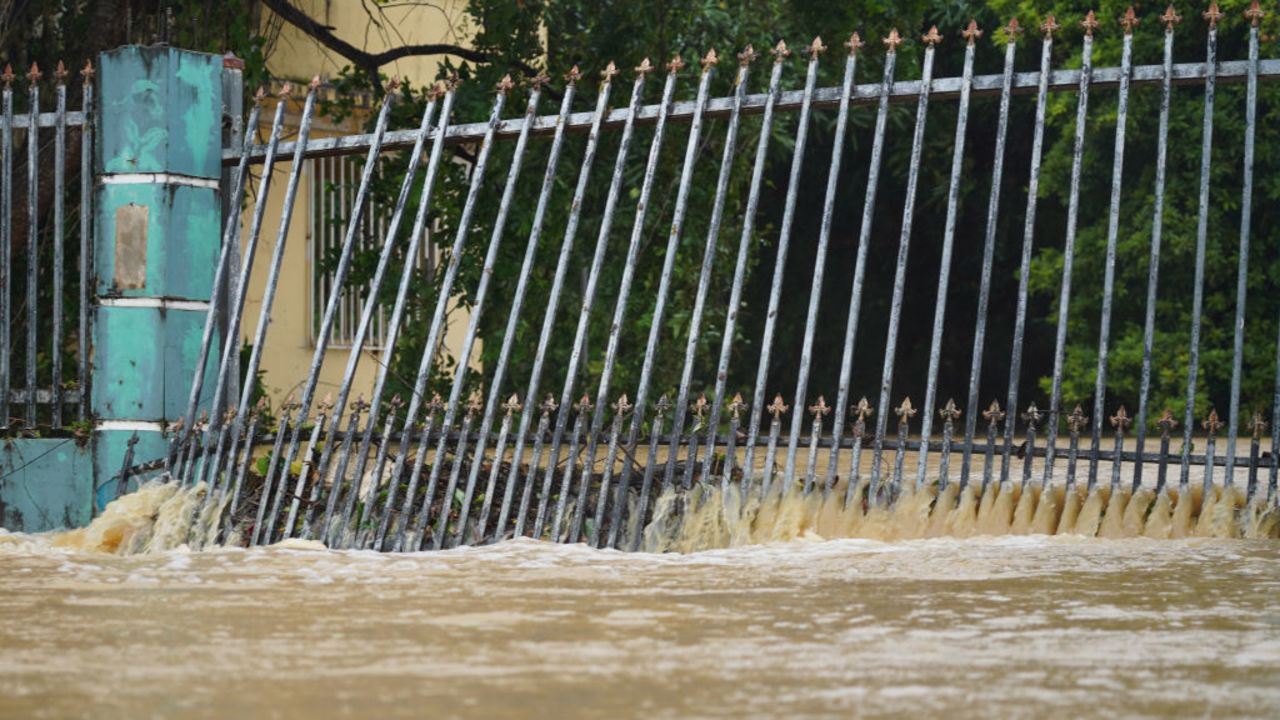 Flood water spills through a fence onto a street in Fajardo, Puerto Rico, as Tropical Storm Ernesto passes through the area on August 14, 2024.. Ernesto grew into a hurricane on August 14, the US National Hurricane Center (NHC) said, after leaving more than 600,000 customers without power in the US territory of Puerto Rico. The storm brushed past the Caribbean island overnight, and was expected to dump up to 10 inches (25 centimeters) of rain in some places, according to NHC. (Photo by Jaydee Lee SERRANO / AFP) (Photo by JAYDEE LEE SERRANO/AFP via Getty Images)