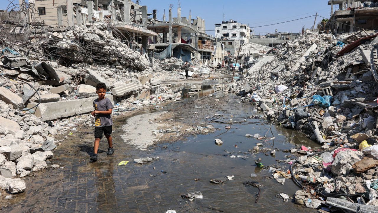 A boy walks through a puddle of sewage water past mounds of trash and rubble along a street in the Jabalia camp for Palestinian refugees in the northern Gaza Strip on August 14, 2024 amid the ongoing conflict in the Palestinian territory between Israel and Hamas. (Photo by Omar AL-QATTAA / AFP) (Photo by OMAR AL-QATTAA/AFP via Getty Images)