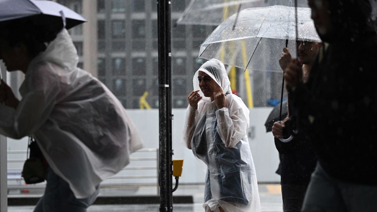 People shield themselves from heavy rain as Typhoon Ampil approaches Tokyo on August 16, 2024.