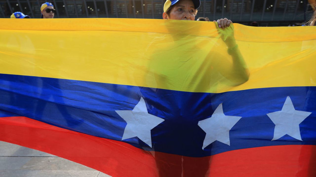 A woman stands behind a Venezuelan flag during a protest called by the Venezuelan opposition for election 'victory' to be recognised in Medellin, Colombia, on August 17, 2024. Venezuelan opposition leader Maria Corina Machado had called for mass gatherings in more than 300 cities in Venezuela and abroad to intensify pressure on Maduro to concede what she says was an overwhelming opposition win in the July 28 presidential polls. (Photo by JAIME SALDARRIAGA / AFP) (Photo by JAIME SALDARRIAGA/AFP via Getty Images)