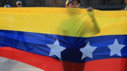 A woman stands behind a Venezuelan flag during a protest called by the Venezuelan opposition for election 'victory' to be recognised in Medellin, Colombia, on August 17, 2024. Venezuelan opposition leader Maria Corina Machado had called for mass gatherings in more than 300 cities in Venezuela and abroad to intensify pressure on Maduro to concede what she says was an overwhelming opposition win in the July 28 presidential polls. (Photo by JAIME SALDARRIAGA / AFP) (Photo by JAIME SALDARRIAGA/AFP via Getty Images)