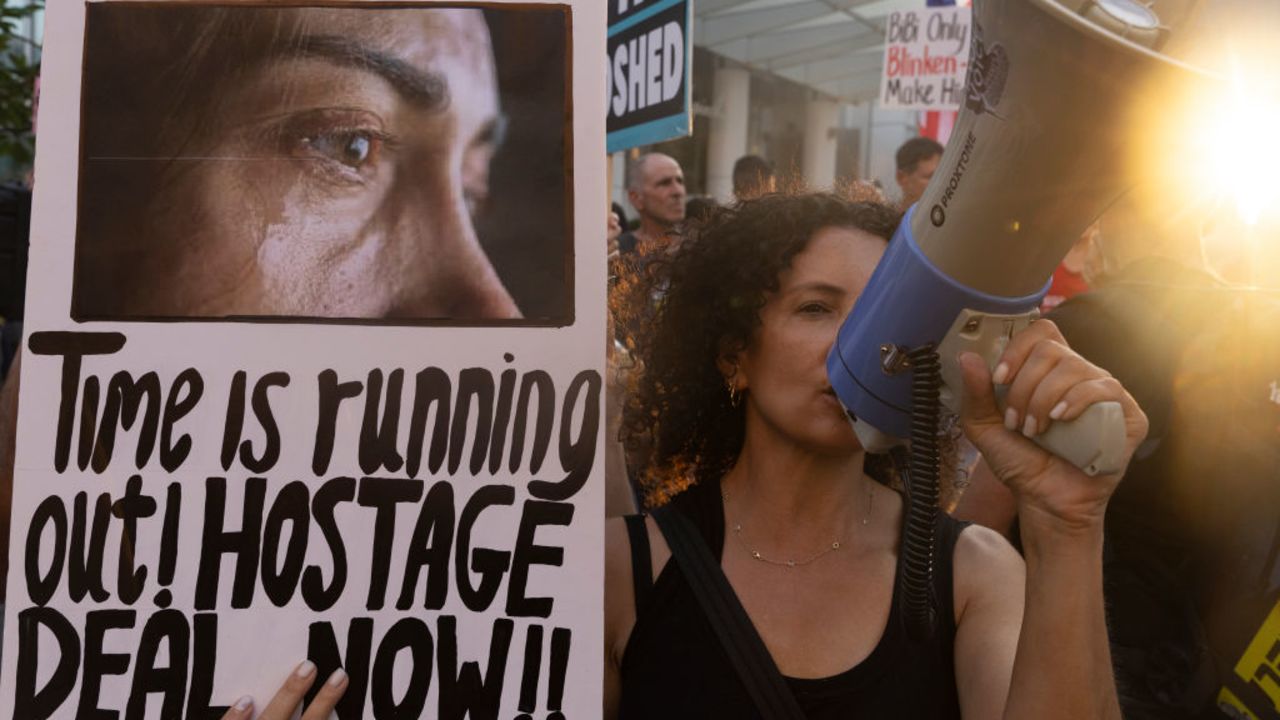 TEL AVIV, ISRAEL - AUGUST 19: Families of hostages who were kidnaped by Hamas on Oct 7 deadly attack and supporters hold signs and US flags during a demonstration outside a press event by US secretary of state Antony Blinken on August 19, 2024 in Tel Aviv, Israel. The US Secretary of State is visiting the region as cease-fire mediators are again sounding notes of cautious optimism. Multi-country talks to end the war in Gaza resume in Cairo this week. (Photo by Amir Levy/Getty Images)