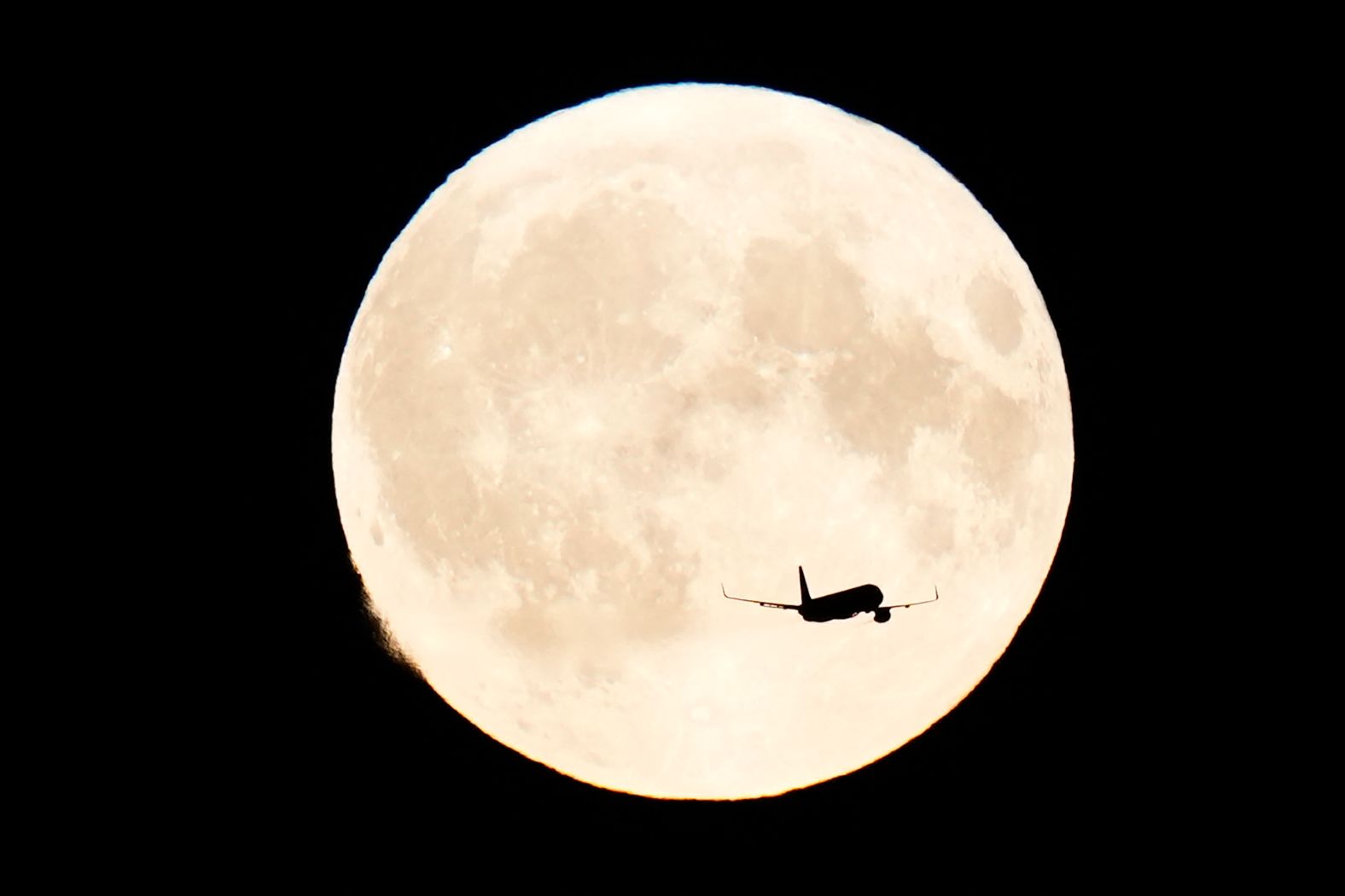 An aircraft flies in front of the super blue moon over Copenhagen, Denmark, on Monday.