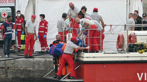 Rescuers carry a body after divers return in Porticello harbor near Palermo, on August 22, 2024, three days after the British-flagged luxury yacht Bayesian sank. Divers searching for six missing people following the sinking of a superyacht off Sicily in a storm have found fifth bodies. The Bayesian, which had 22 people aboard including 10 crew, was anchored some 700 metres from port before dawn when it was struck by a waterspout. Among the six missing were UK tech entrepreneur Mike Lynch and his 18-year-old daughter Hannah, and Jonathan Bloomer, the chair of Morgan Stanley International, and his wife Judy. (Photo by Alberto PIZZOLI / AFP) (Photo by ALBERTO PIZZOLI/AFP via Getty Images)