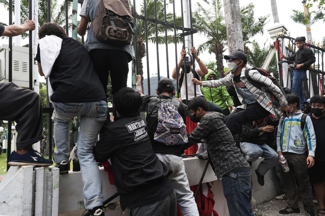 Para pengunjuk rasa memanjat pagar di gedung DPR di Jakarta.