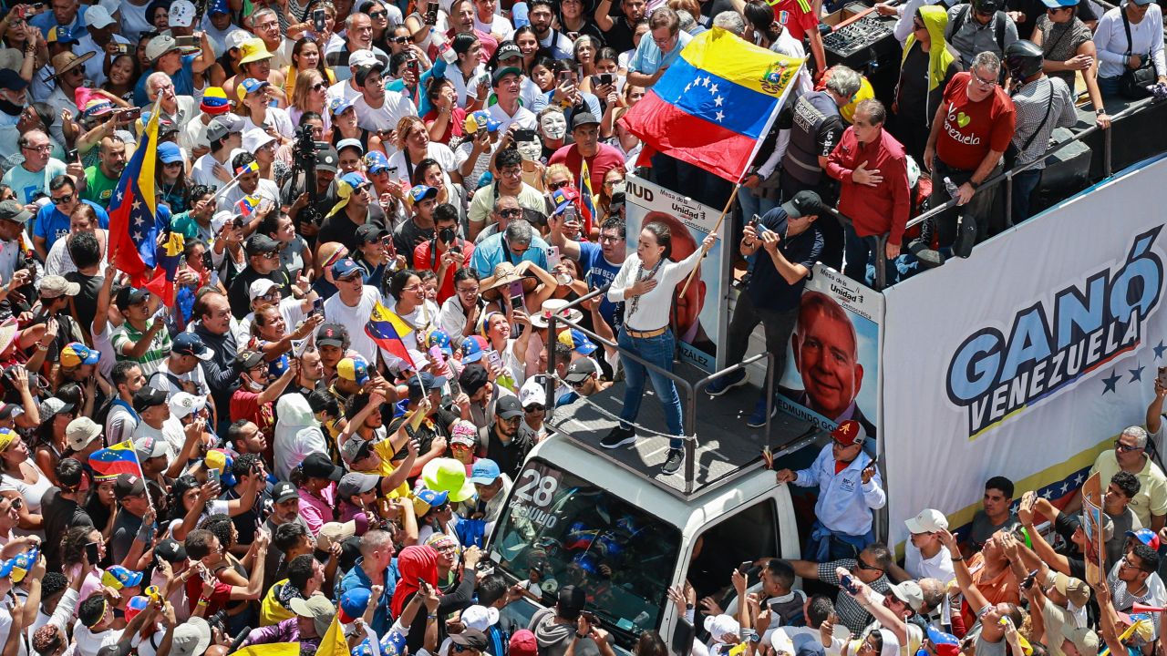 CARACAS, VENEZUELA - AUGUST 17: Opposition leader Maria Corina Machado raises a Venezuelan flag during the 'Gran Protesta Mundial por la Verdad' opposition protest on August 17, 2024 in Caracas, Venezuela. President of Venezuela Nicolas Maduro was declared as the winner of the 2024 presidential election over his rival, Edmundo Gonzalez. The result has been questioned by the opposition and internationally. According to the opposition leader Maria Corina Machado, the result announced by the 'Consejo Nacional Electoral' (CNE) does not reflect the decision made by the Venezuelans during the election.  (Photo by Jesus Vargas/Getty Images)