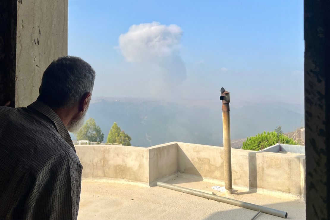 A man watches smoke billow after an Israeli airstrike in village of Qsair, in southern Lebanon, on August 25, 2024.