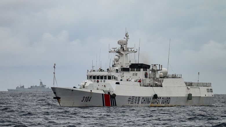A China Coast Guard ship (R) and a vessel identified by the Philippine Coast Guard as a Chinese navy ship (background L) are seen from the Philippine Coast Guard vessel BRP Cabra during a supply mission to Sabina Shoal in disputed waters of the South China Sea on August 26, 2024.