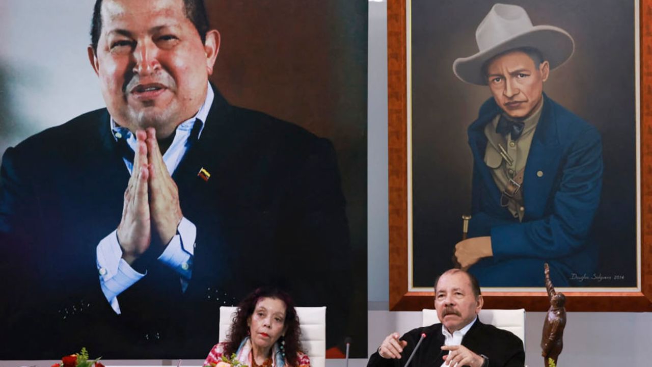 This handout picture released by the Nicaraguan Presidency shows Nicaraguan President Daniel Ortega (R) speaking next to his wife and Vice President Rosario Murillo and in front of a giant photo of the late Venezuelan former president Hugo Chavez (L-back) during the XI ALBA-T Extraordinary Summit (virtual) in Managua on August 26, 2024. (Photo by Cesar PEREZ / Nicaraguan Presidency / AFP) / RESTRICTED TO EDITORIAL USE - MANDATORY CREDIT "AFP PHOTO / NICARAGUAN PRESIDENCY / CESAR PEREZ" - NO MARKETING NO ADVERTISING CAMPAIGNS - DISTRIBUTED AS A SERVICE TO CLIENTS (Photo by CESAR PEREZ/Nicaraguan Presidency/AFP via Getty Images)