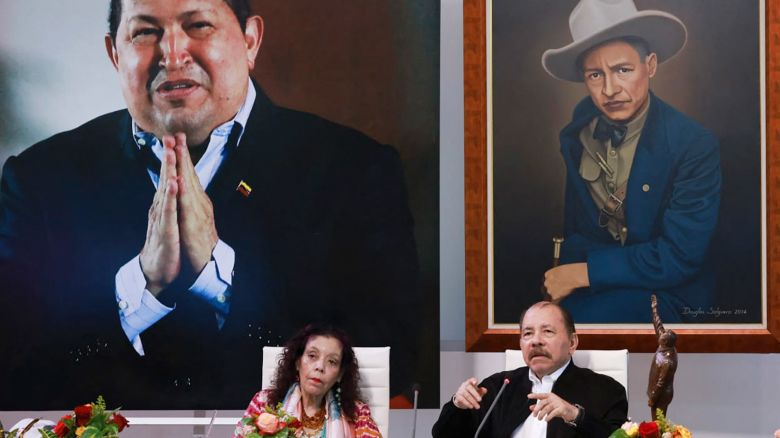 This handout picture released by the Nicaraguan Presidency shows Nicaraguan President Daniel Ortega, right, speaking next to his wife and Vice President Rosario Murillo and in front of a giant photo of the late Venezuelan former president Hugo Chavez, back and left, during the virtual XI ALBA-TCP Extraordinary Summit in Managua, Nicaragua on August 26, 2024.