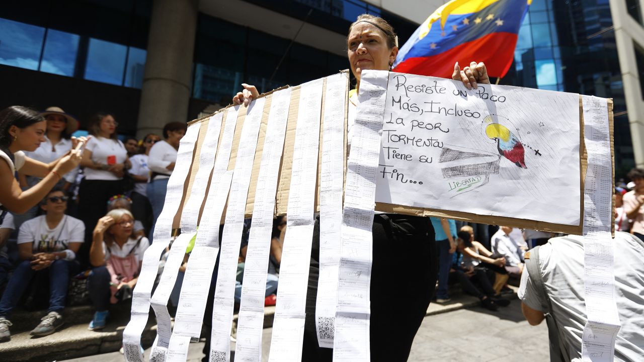 A woman holds electoral records on a board during a rally called by the opposition in Caracas on August 28, 2024. Venezuela's opposition ers rallied on August 28, a month after the disputed re-election of President Nicolas Maduro, who armoured his cabinet with a strongman at the helm of law and order. (Photo by Pedro Rances Mattey / AFP) (Photo by PEDRO RANCES MATTEY/AFP via Getty Images)