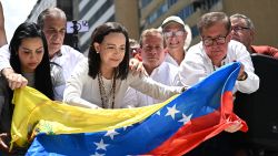 Venezuelan opposition leader Maria Corina Machado places a Venezuelan flag in front of her truck during a rally in Caracas on August 28, 2024. Venezuela's opposition supporters rallied on August 28, a month after the disputed re-election of President Nicolas Maduro, who armoured his cabinet with a strongman at the helm of law and order. (Photo by JUAN BARRETO / AFP) (Photo by JUAN BARRETO/AFP via Getty Images)