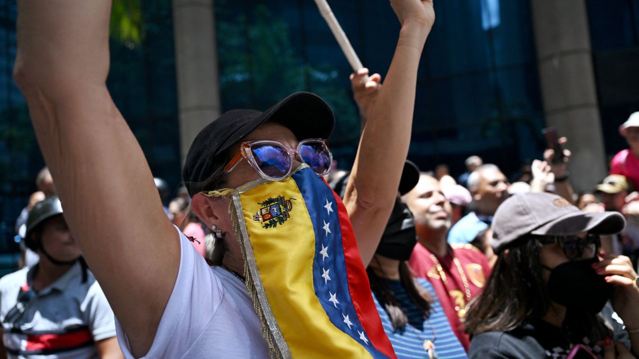 A woman covers her face with a Venezuelan flag during a rally called by the opposition in Caracas on August 28, 2024. Venezuela's opposition ers rallied on August 28, a month after the disputed re-election of President Nicolas Maduro, who armoured his cabinet with a strongman at the helm of law and order. (Photo by JUAN BARRETO / AFP) (Photo by JUAN BARRETO/AFP via Getty Images)
