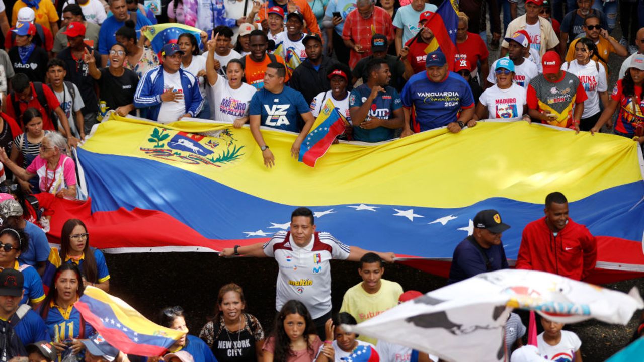 People wave a giant Venezuelan flag during a rally called by the ruling party in Caracas on August 28, 2024. The Venezuelan ruling party called for a mobilization on August 28, to 'celebrate' Maduro's victory, which has been rejected by the United States, the European Union and several countries in the region. (Photo by Pedro Rances Mattey / AFP) (Photo by PEDRO RANCES MATTEY/AFP via Getty Images)