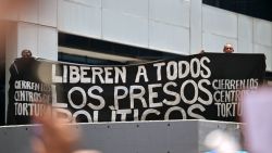 People hold a banner asking for freedom to political prisoners during a rally called by the ruling party in Caracas on August 28, 2024. The Venezuelan ruling party called for a mobilization on August 28, to 'celebrate' Maduro's victory, which has been rejected by the United States, the European Union and several countries in the region. (Photo by Juan BARRETO / AFP) (Photo by JUAN BARRETO/AFP via Getty Images)