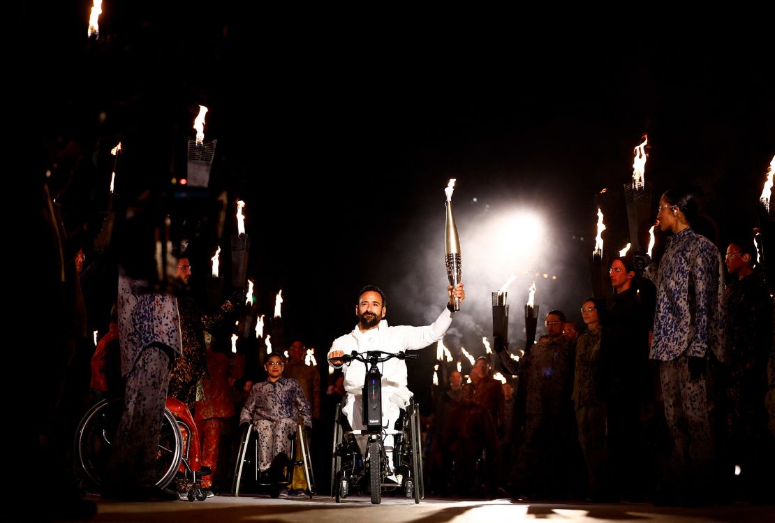 France's Michaël Jérémiasz holds the Paralympic flame during the torch relay as part of the opening ceremony.