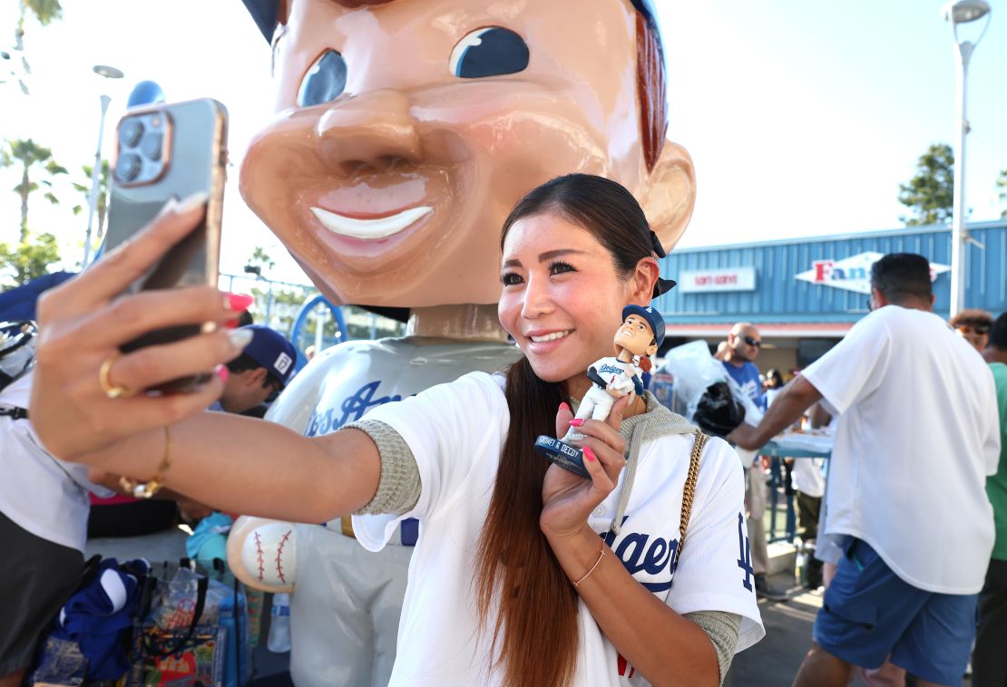 Los Angeles, California August 28, 2024-Fan Atsugi Ilene takes a picture with her bobblehead of Dodgers Shohei Ohtani before a game with the Orioles at Dodger Stadium Wednesday. (Skalij/Los Angeles Times via Getty Images)