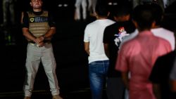 A member of the National Migration Service (SNM) observes Ecuadorian migrants, with their hands and feet handcuffed, queuing to climb a plane at the Albrook Gelabert airport in Panama City on August 29, 2024, during their deportation. Panama on Thursday deported 30 Ecuadorian migrants who entered the country through the inhospitable Darien jungle, bordering Colombia, as part of an agreement signed in July with the United States. (Photo by MARTIN BERNETTI / AFP) (Photo by MARTIN BERNETTI/AFP via Getty Images)