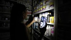 TOPSHOT - An employee searches for a product in a cosmetics store during a blackout in Caracas on August 30, 2024. A blackout early Friday morning left Venezuela, including the capital, Caracas, in darkness, reported the government, which attributed the failure to a "sabotage" of the system by the opposition in the midst of its claims of electoral fraud. (Photo by Pedro Rances Mattey / AFP) (Photo by PEDRO RANCES MATTEY/AFP via Getty Images)