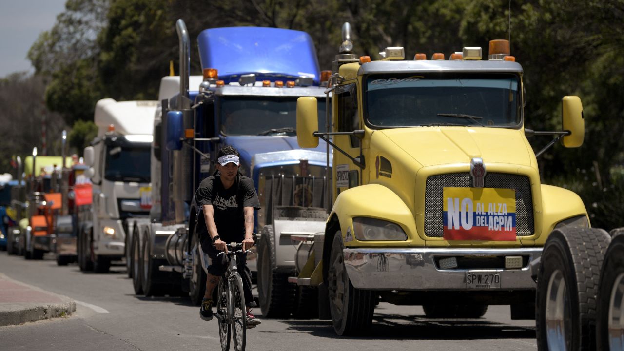 A man rides past cargo trucks attending a protest against the increase in fuel prices in Bogota on August 30, 2024. Colombia's cargo trucker drivers protested on Friday with their vehicles in several cities in the country against the increase in diesel prices announced a week ago by the government. (Photo by Daniel MUNOZ / AFP) (Photo by DANIEL MUNOZ/AFP via Getty Images)