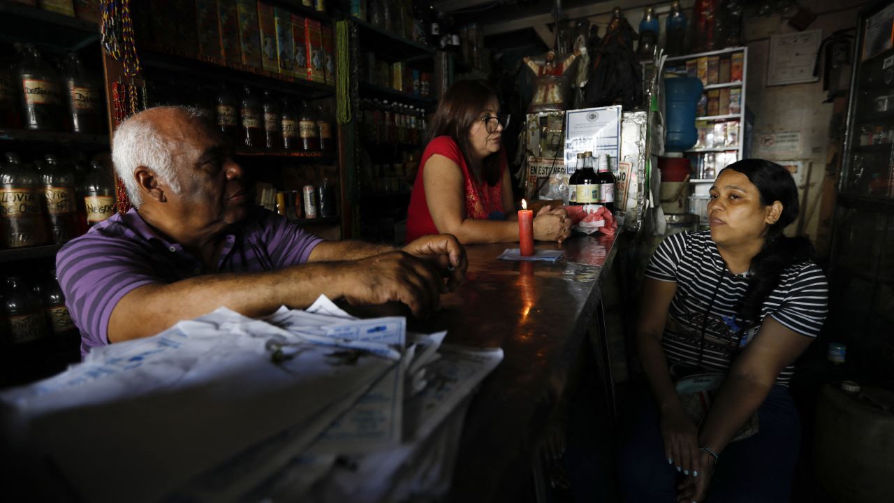 Workers talk near a candle in an establishment during a blackout in Caracas on August 30, 2024. A blackout early Friday morning left Venezuela, including the capital, Caracas, in darkness, reported the government, which attributed the failure to a "sabotage" of the system by the opposition in the midst of its claims of electoral fraud. (Photo by Pedro Rances Mattey / AFP) (Photo by PEDRO RANCES MATTEY/AFP via Getty Images)