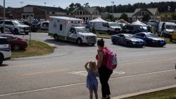 A young girl and her mother watch as law enforcement and first responders surround Apalachee High School in Winder, Georgia, on September 4, 2024, after a shooting was reported. Four people were killed and nine wounded in the school shooting on Wednesday, the Georgia Bureau of Investigation said. "Four dead. An additional nine taken to various hospitals with injuries. Suspect in custody and alive. Reports that the suspect has been 'neutralized' are inaccurate," the bureau said in a social media post.