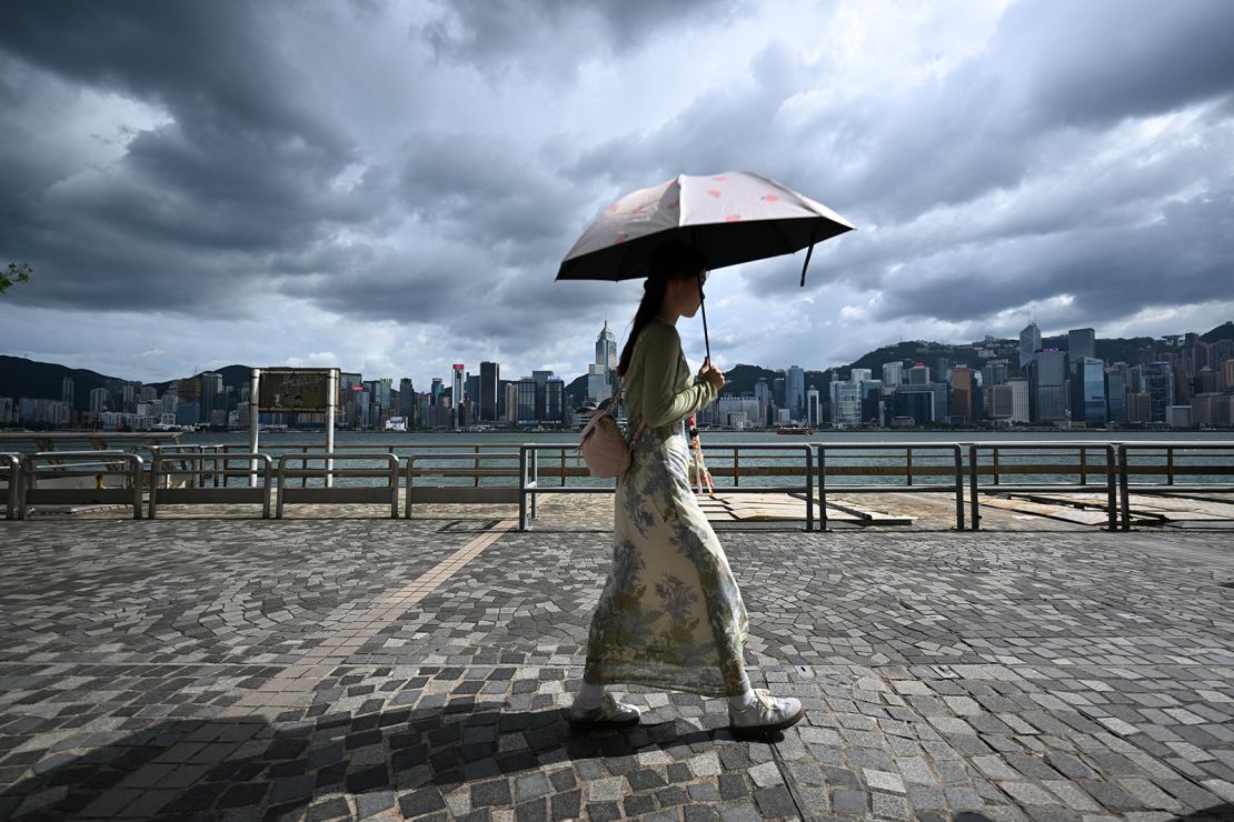 A woman holds an umbrella while walking on the promenade at Victoria Harbour in Hong Kong on September 5, as Super Typhoon Yagi moved across the South China Sea.