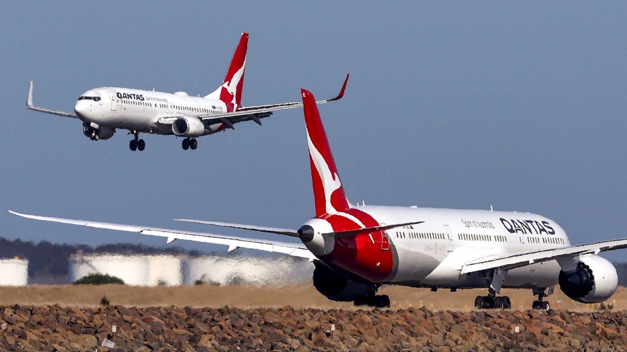 This photo taken on September 4, 2024 shows a Qantas Airways Boeing 737-800 plane coming in to land next to a Qantas Airways Boeing 787 Dreamliner aircraft preparing to take-off at Sydney International Airport.