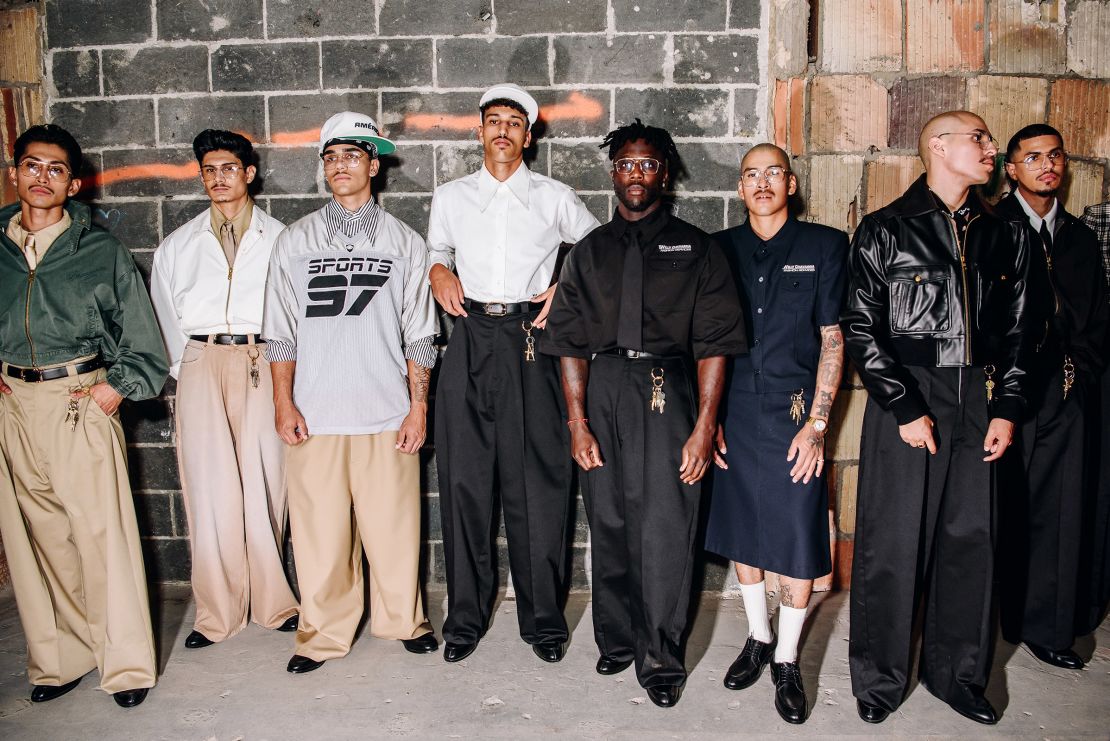 Models line up backstage at Willy Chavarria in wide, belted pants, starched tailoring and a bunch of dangling keys as accessories.