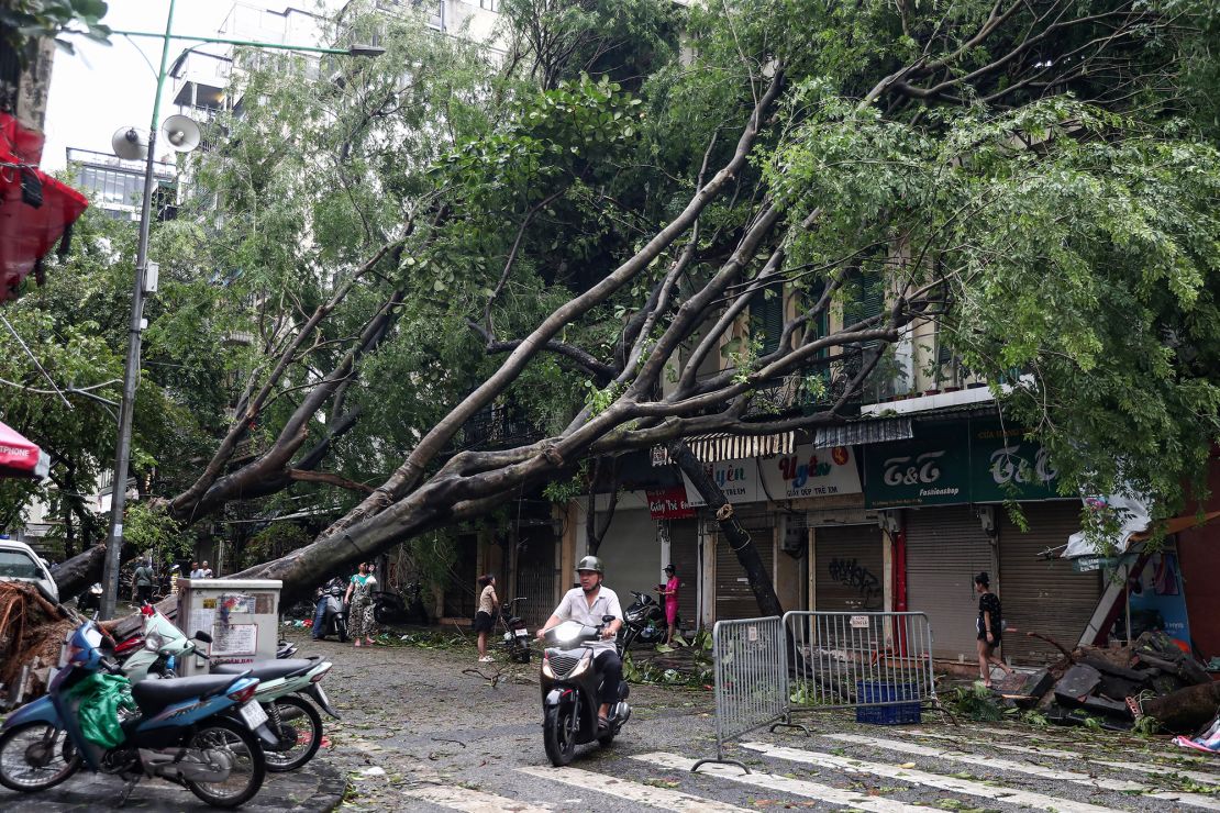 A man rides his motorbike past fallen trees on September 8, 2024 after Typhoon Yagi hit Hanoi.