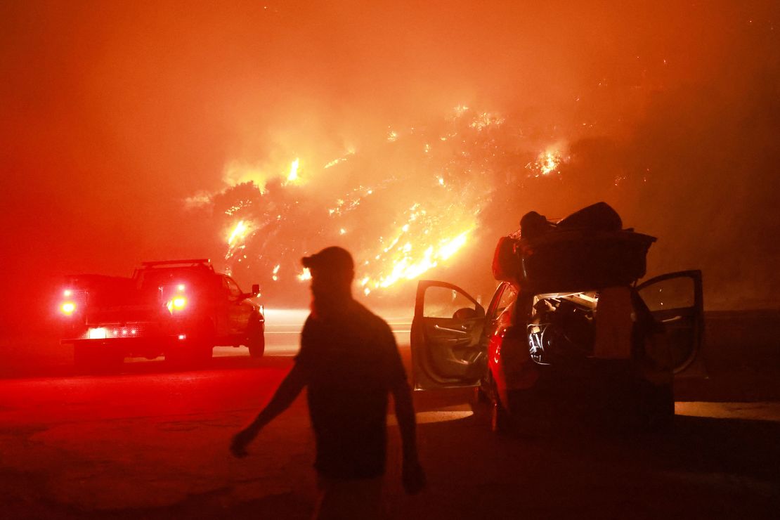 A resident walks by his car packed with belongings as Highway 330 is engulfed by the Line Fire near Running Springs, California, on September 7, 2024.